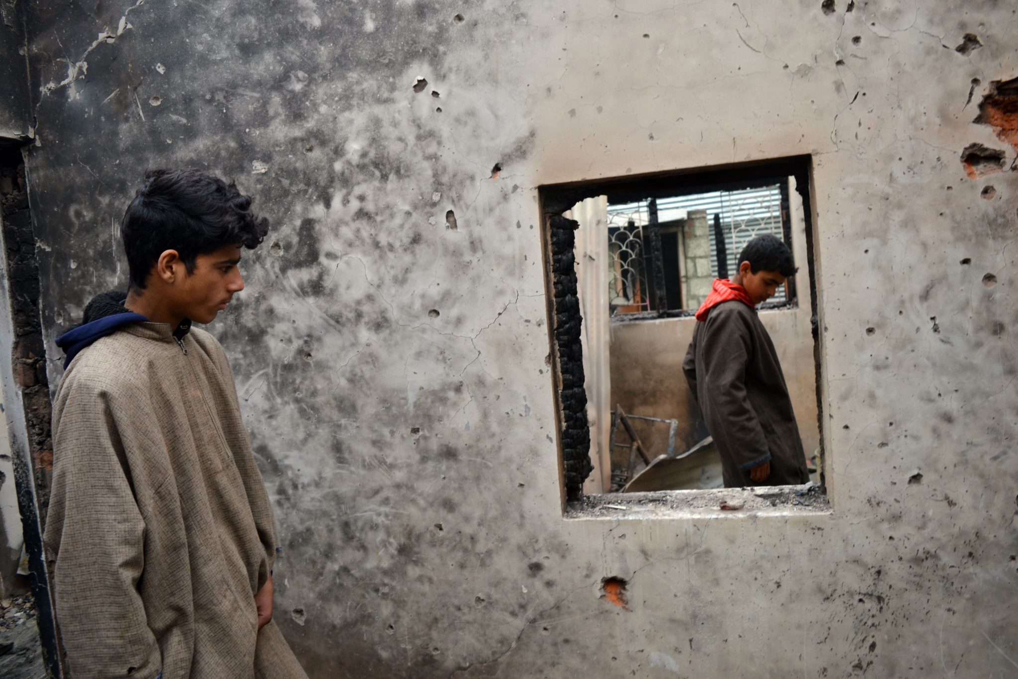 Dec. 9, 2018, Srinagar, Kashmir — Young boys inspect war-ravaged houses in their neighborhood where militants were holed up during a gunbattle with Indian government forces. A 14-year-old boy was among the three militants killed.