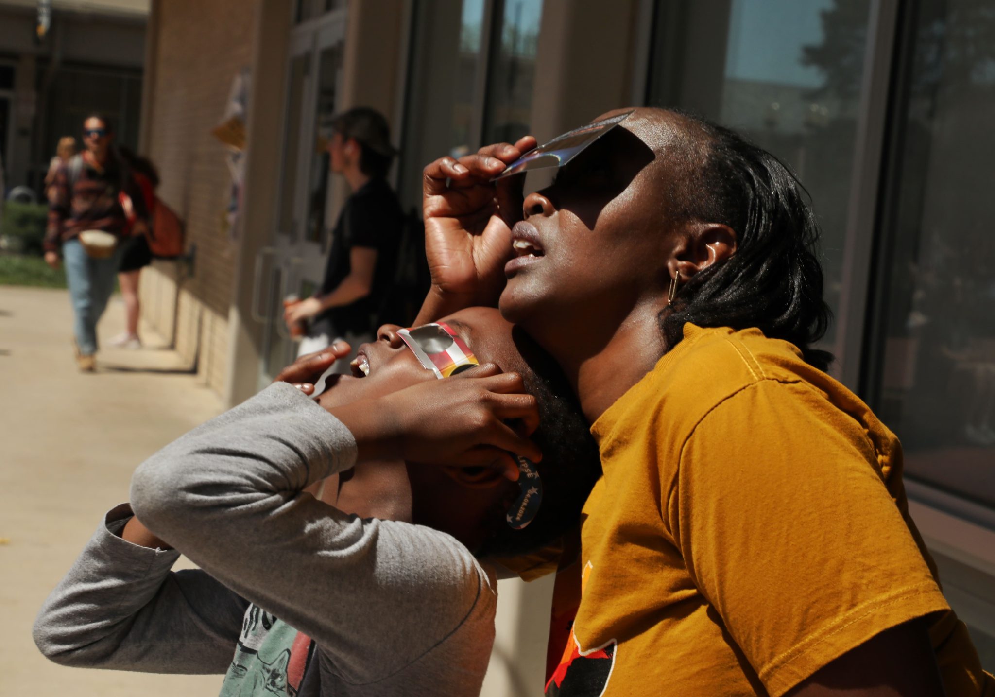 April, 8, 2024, Columbia, Missouri - Terry Nzau watching total solar eclipse with her 5 year old son on University of Missouri Columbia campus.